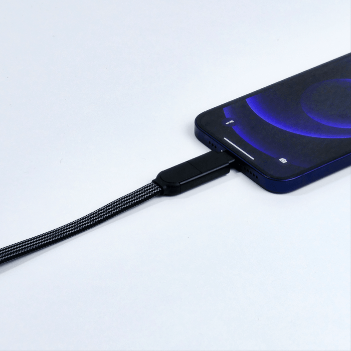 inCharge® X Max - 100W, 6in1 long cable - inCharge® X Max - 100W, 6in1 long cable - Lava Black - Black braided 6-in-1 charging cable connected to a modern smartphone with a dark screen and blue glow. - Rolling Square inCharge® X Max - 100W, 6in1 long cable - Lava Black - Black braided 6-in-1 charging cable connected to a modern smartphone with a dark screen and blue glow. - Rolling Square