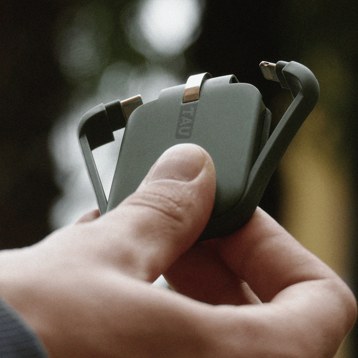 TAU® - Always-charged power bank - TAU® - Always-charged power bank - Charcoal Black - Compact agave green TAU power bank with built-in charging cables held in hand outdoors. - Rolling Square TAU® - Always-charged power bank - Charcoal Black - Compact agave green TAU power bank with built-in charging cables held in hand outdoors. - Rolling Square