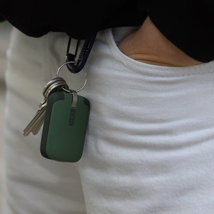 TAU® - Always-charged power bank - TAU® - Always-charged power bank - Charcoal Black - Compact agave green power bank attached to keyring held against white shirt. - Rolling Square TAU® - Always-charged power bank - Charcoal Black - Compact agave green power bank attached to keyring held against white shirt. - Rolling Square