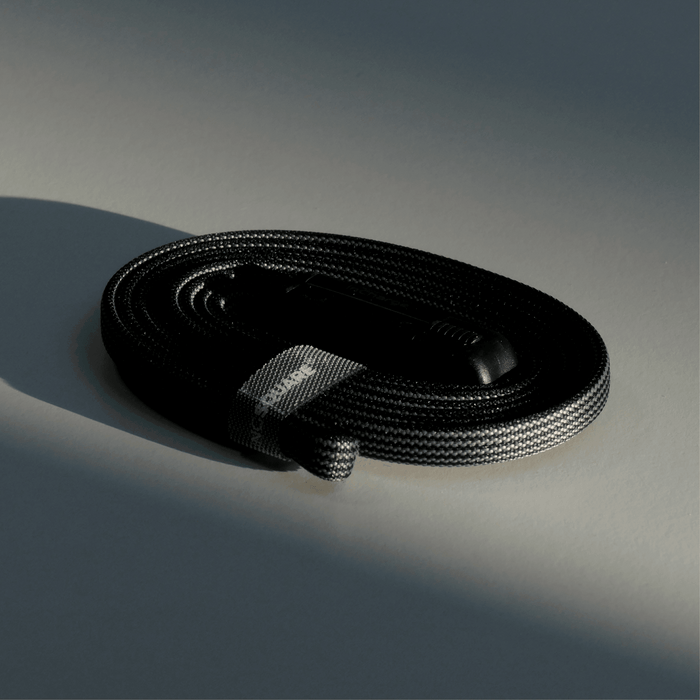 inCharge® X Max - 100W, 6in1 long cable - Lava Black - Coiled black braided 6-in-1 charging cable with fabric tie labeled inCharge in low light. - Rolling Square